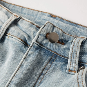Detail of light blue denim waistband featuring a silver metal button and orange stitching