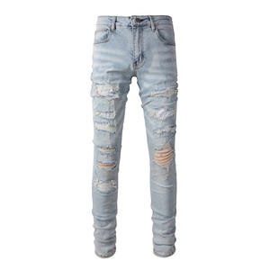 Men's light blue slim fit distressed stacked jeans with rhinestone patches and holes