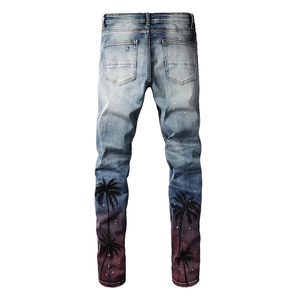 Macro detail of men's slim fit light blue jeans with black palm tree prints and paint spots