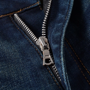 Gros plan détaillé d'un jean en denim bleu foncé avec fermeture éclair argentée et coutures orange