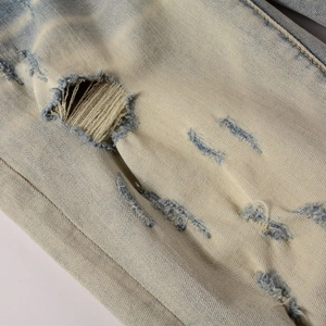 Vue détaillée du denim bleu clair avec délavage vintage et trous déchirés style rue