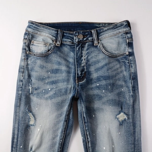 Detail view of washed blue denim with white paint splatters and handmade distressed holes