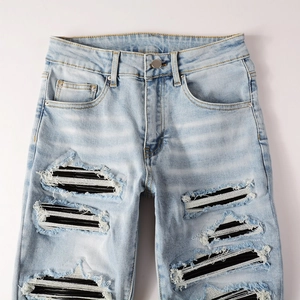 Detail of high street distressed blue jeans with black and white striped patch inside