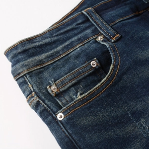 Gros plan sur le denim bleu avec rivets métalliques renforcés et coutures sur le pantalon