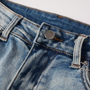 Detail of light blue denim jeans waist with silver button and cat-whisker wash texture