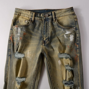 Detailaufnahme der Vintage-Denim-Textur mit Farbspritzern und modischen Rissen im Stoff