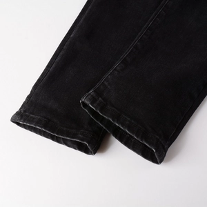 Close-up of distressed hem details on men's black slim fit stretch denim jeans