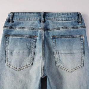 Close-up of the back pockets on light blue washed distressed denim jeans for men