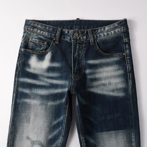 Dettaglio di jeans blu slim fit con lavaggio pesante e trama baffata sul tessuto
