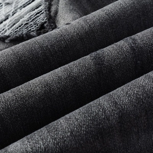 Vue détaillée du tissu denim gris foncé vieilli avec bords effilochés et texture