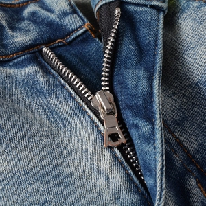 Detail of silver metal zipper and precise stitching on light blue slim fit denim jeans