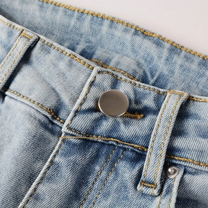 Macro detail of men's jeans waist with a smooth metal button and contrast stitching