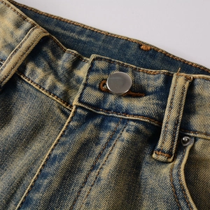 Detail von Vintage-Denim in Blau mit gelber Waschung und Metallknopf-Verschluss