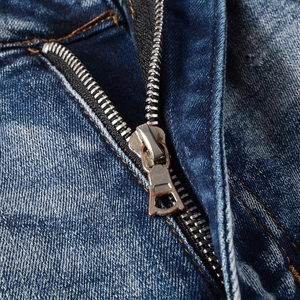 Close-up of metal zipper fly and contrast stitching on washed blue slim fit denim jeans