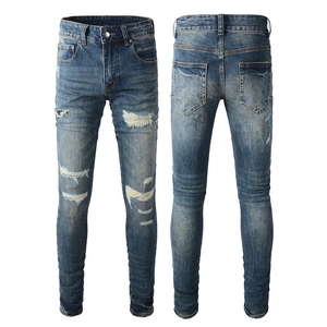 Detailed close-up of blue distressed jeans with ripped patches and whiskered texture