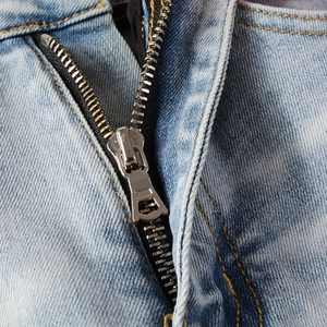 Close-up of high street slim fit blue denim jeans featuring premium metal zipper and yellow stitching