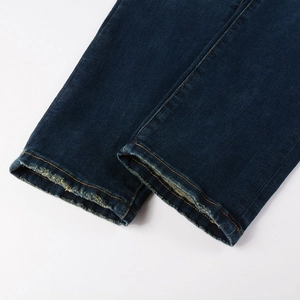 Close-up of deep indigo denim jeans with raw hem and classic yellow double stitching