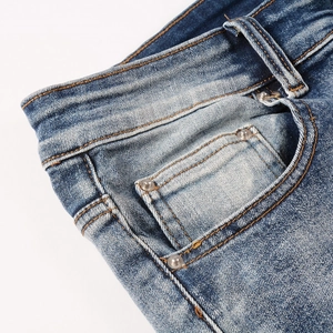 Detailed close-up of blue denim jeans showing fabric texture, orange stitching and rivets