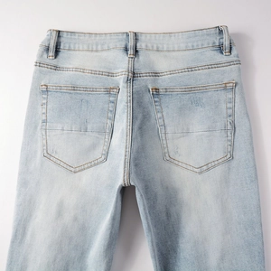 Detail view of the back pockets and washed finish of light blue distressed jeans