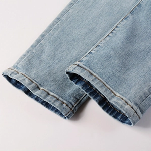 Detailed close-up of light blue denim jeans hem with yellow double-needle stitching