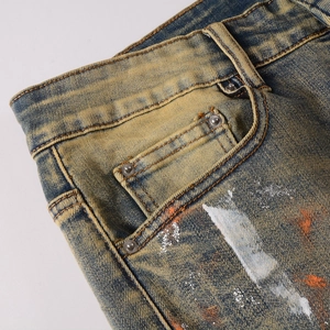 Detail einer Vintage-Bluejeans mit Distressed-Waschung und künstlerischem Farbspritz-Design
