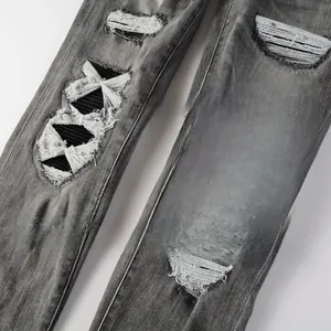 Détail d'un jean gris foncé délavé avec des déchirures style DIY et nœuds blancs aux genoux