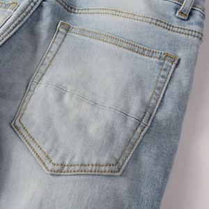 Detailed close-up of light blue denim rear pocket with yellow contrast stitching on jeans