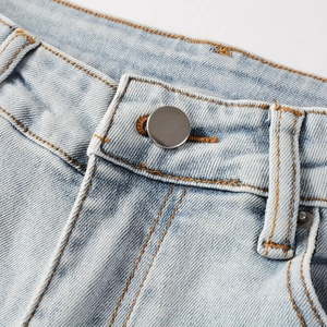 Close-up of light blue washed denim jeans waist with classic orange stitching and metal button
