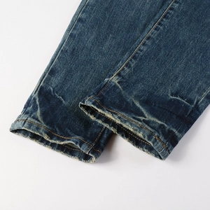 Close-up of distressed denim hem with detailed stitching on navy blue men's slim jeans