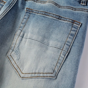Macro shot of back pocket on washed blue jeans with distressed details and stitching