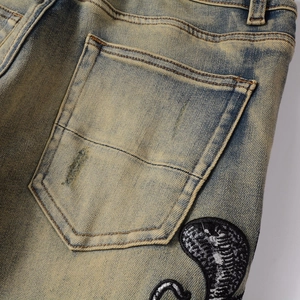 Détail du jean vintage avec délavage dirty wash et broderie cobra sur la poche