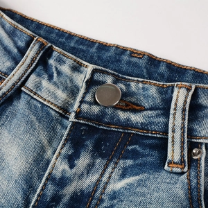 Close-up of vintage metal button and stitching details on dark blue washed denim jeans