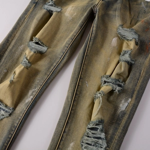 Detailansicht der Denim-Struktur mit Farbspritzern und rissigen Löchern im Vintage-Look