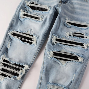 Light blue distressed jeans with large ripped holes and black white striped inner patches