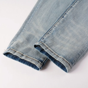 Close-up of light blue jeans hem with snow wash effect and yellow stitching detail