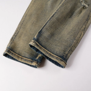 Gros plan sur un jean vintage délavé jaune avec détails usés et coutures doubles