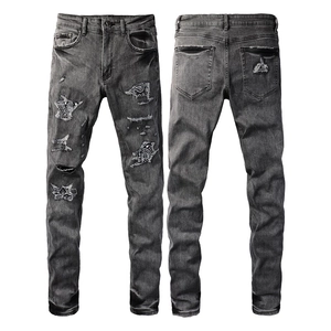 Detail of slim-fit gray jeans with vintage distressing and paisley pattern patchwork patches