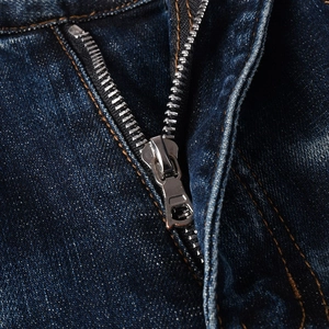 Dettaglio della zip in metallo e cuciture arancioni su jeans in denim blu scuro