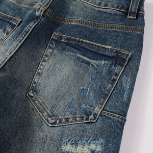 Detailed view of heavy stitching, worn-out back pockets and patch details on blue denim jeans