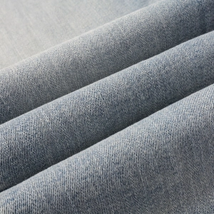 Detailed view of light blue stretch denim fabric with premium twill weaving texture