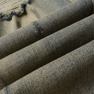 Détail macro du denim délavé vintage avec déchirures usées et texture sergée
