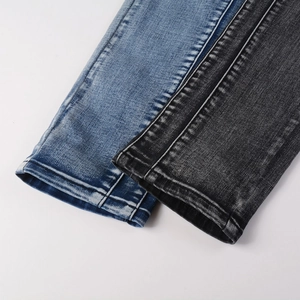 Vue détaillée de l'ourlet du jean montrant les coutures et la texture du tissu délavé