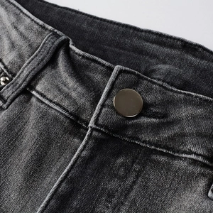 Détail macro du jean high-street avec bouton métallique et texture denim délavé