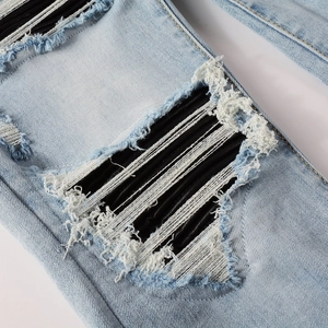 Detailed macro view of distressed light blue denim with black striped patch and ripped holes