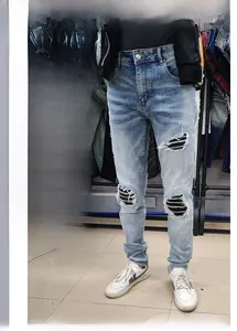 Detail of light blue distressed skinny jeans with black ribbed fabric inserts at the knees