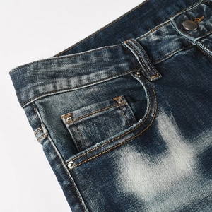 Dettaglio di jeans blu vintage con cuciture arancioni, rivetti e trama lavata