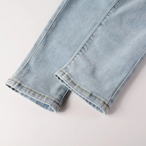 Detail of light blue denim jeans cuff featuring double stitching and twill texture