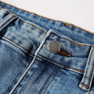 Detailed macro view of light blue denim waist with orange stitching and metal button