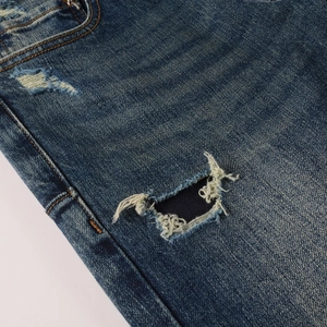 Macro shot of distressed denim fabric with ripped details on dark blue men's jeans