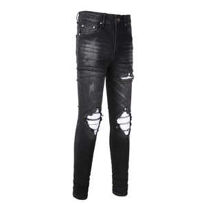 Detail of vintage washed black denim pants featuring knee distressing and stripe accents